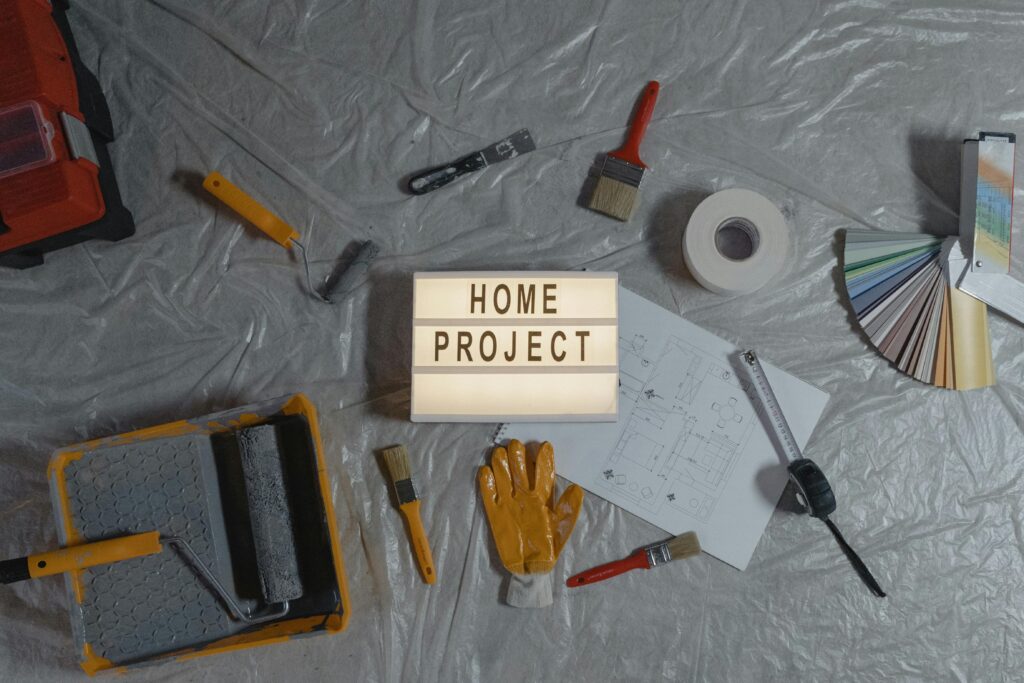 Flat lay of home improvement tools, paint samples, and blueprints for a DIY project.
