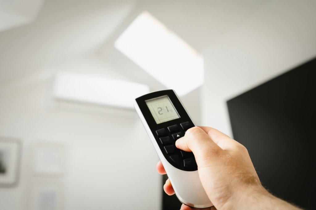 pexels-photo-16695385-16695385 Close-up of a man using a remote to control air conditioning indoors.